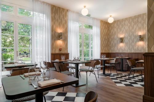 un restaurante con mesas, sillas y ventanas en Hôtel de la Poste, en Beaune