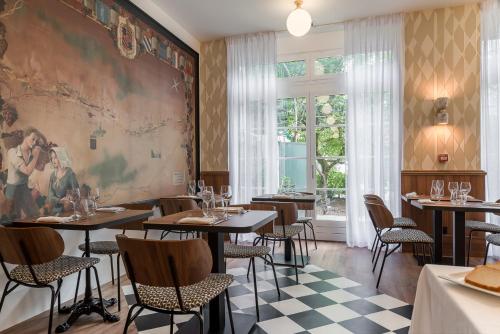 a restaurant with tables and chairs and a large painting on the wall at Hôtel de la Poste in Beaune