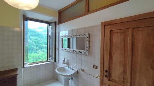 baño con lavabo, espejo y ventana en Ca Giulietto Antico Casale in Lunigiana en Pontremoli