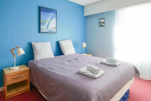 a blue bedroom with a bed with towels on it at Appartement une chambre avec vue sur la baie des Sables 4 personnes in Les Sables-dʼOlonne