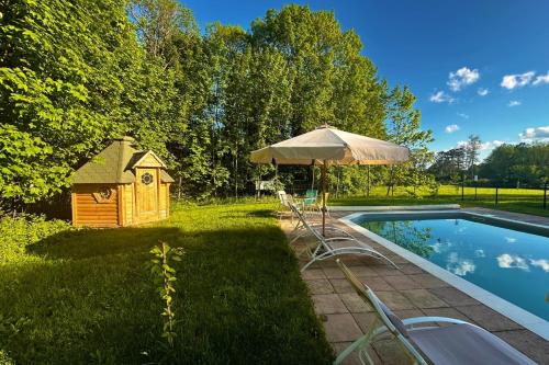 un patio trasero con piscina, sombrilla y casa en Proche Vittel et Contrexéville château Viendal et son beau parc, 