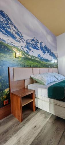 a bedroom with a mountain mural on the wall at Apartment FIMM in Veľká Lomnica