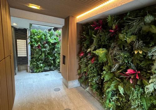 a hallway with a green wall with plants at Sakura Cross Hotel Ueno Iriya in Tokyo
