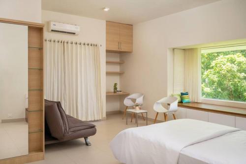 a bedroom with a bed and a chair and a window at Premium 5 BR full pool villa by lake close to Vagamon in Muttam