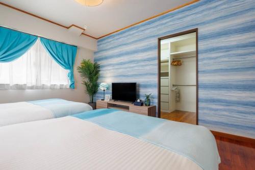 a hotel room with two beds and a television at 恩納村飲食店の中心地ビーチまで徒歩3分最大12名貸切コーディアルステイ in Fuzuchi
