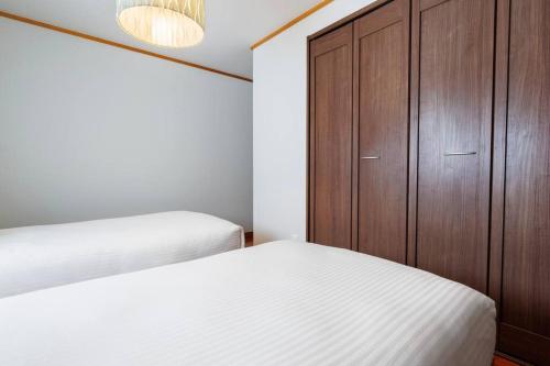 a bedroom with two beds and a wooden cabinet at 恩納村飲食店の中心地ビーチまで徒歩3分最大12名貸切コーディアルステイ in Fuzuchi