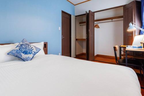 a bedroom with a large white bed and a desk at 恩納村飲食店の中心地ビーチまで徒歩3分最大12名貸切コーディアルステイ in Fuzuchi