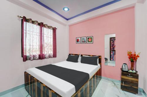 ein Schlafzimmer mit einem Bett und einer rosa Wand in der Unterkunft OYO Flagship R K Marriage Hall and Guest House in Bihta