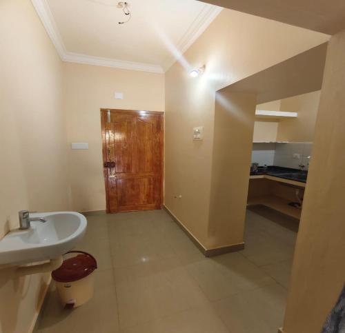 a bathroom with a sink and a wooden door at Arumugam Residency AC in Thiruchendur