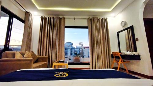 a bedroom with a bed and a couch and a window at Hotel Swat Rezidor by Khan Familia Travels in Swat