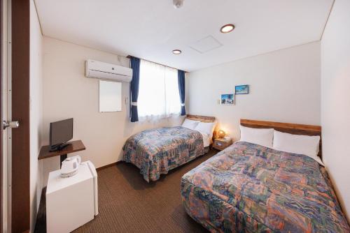 um quarto de hotel com duas camas e uma televisão em ホテルノマド日立 em Hitachi