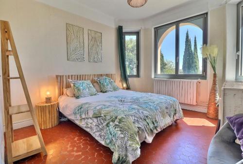 ein Schlafzimmer mit einem Bett mit einer Leiter und zwei Fenstern in der Unterkunft Domaine du Peymian-Villa Art Deco in La Ciotat