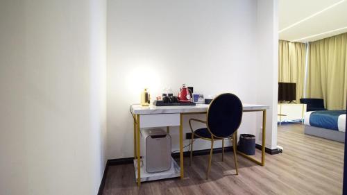 Cette chambre comprend un bureau, une chaise et un lit. dans l'établissement Best Stay at Kozi Square, à Kuching