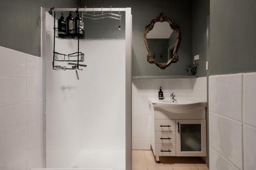 a bathroom with a shower with a sink and a mirror at Cavell Street Cottage in West Hobart in Hobart