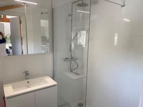 a white bathroom with a shower and a sink at Het Duinenhuisje in Oostduinkerke