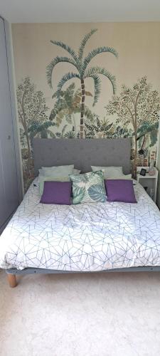 a bedroom with a large bed with palm trees on the wall at Jolie vue surplomb village grand studio Phannie 50m cures parking et Wi-Fi haut débit in Amélie-les-Bains-Palalda