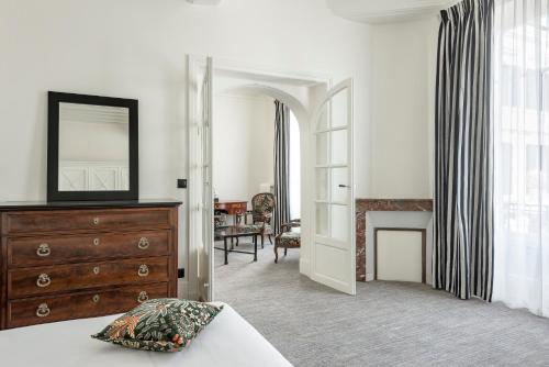 ein Schlafzimmer mit einer Kommode und einem Spiegel sowie ein Wohnzimmer in der Unterkunft Hôtel de la Poste in Beaune