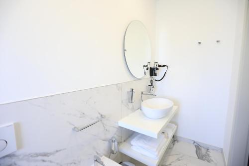 uma casa de banho branca com um lavatório e um espelho em Residenza Arena em Tropea