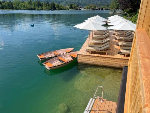 a dock with two boats and umbrellas on a lake at Strandhotel Margaretha in St. Wolfgang