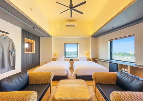 那覇市にあるホテル・アンドルームス那覇ポートのベッド2台とソファが備わるホテルルームです。