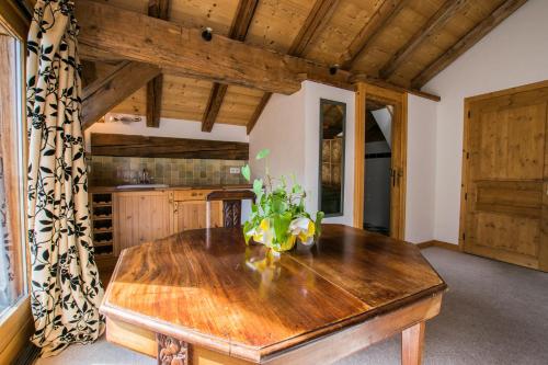 une cuisine avec une table en bois et un vase. dans l'établissement La Ferme du Château, à La Chapelle-dʼAbondance