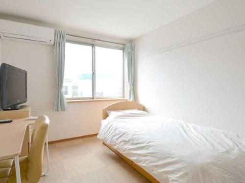 a bedroom with a bed and a desk and a television at Minshuku Hirono in Ōyauchi