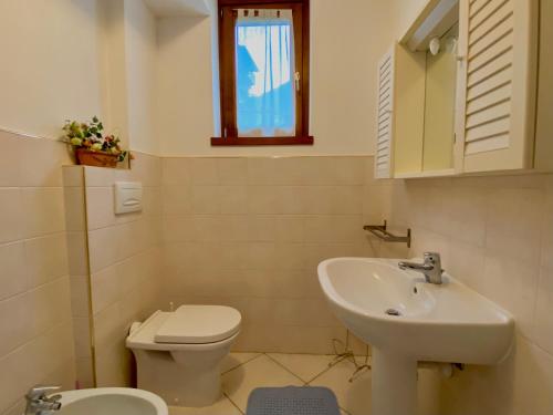 La salle de bains blanche est pourvue d'un lavabo et de toilettes. dans l'établissement residenza in pieno centro storico Borno, à Borno