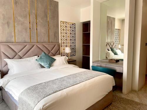 1 dormitorio con 1 cama blanca grande y espejo en Le Levels Residency en Dammam