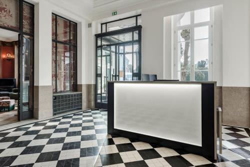 a blank white board in a lobby with a checkered floor at Hôtel de la Poste in Beaune
