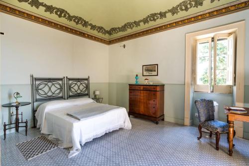 a bedroom with a bed and a desk and a window at Villa Voces in Catania