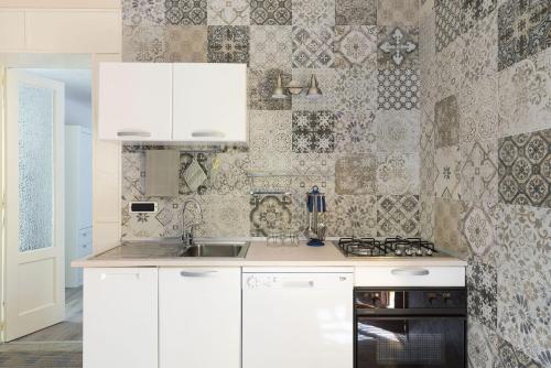 a kitchen with white cabinets and a tile wall at Casa Spisone in Taormina