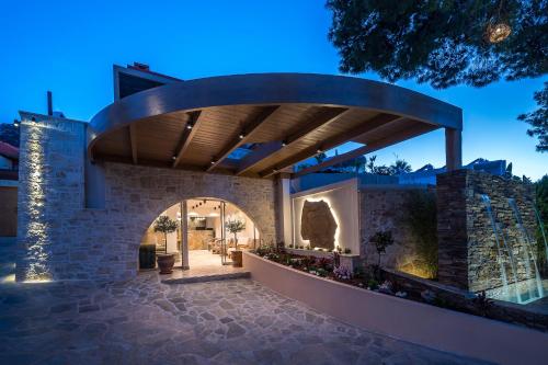 a house with a stone wall with a wooden roof at Esperides Resort Crete, The Authentic Experience in Hersonissos