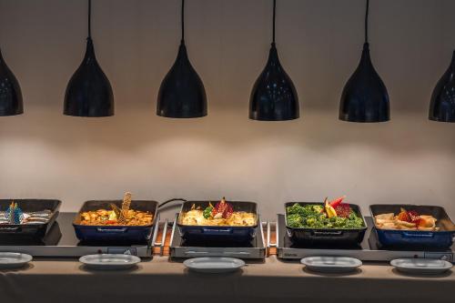 a buffet with several trays of food on a table at Esperides Resort Crete, The Authentic Experience in Hersonissos