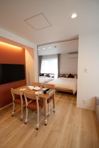 a living room with a table and a bed at Apartment Hotel Tenjin TUMUGU in Fukuoka