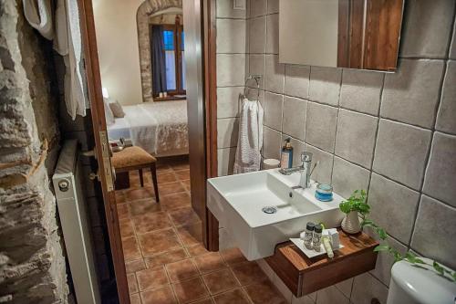 a bathroom with a white sink and a bed at Μountain Whispers in Mouresi