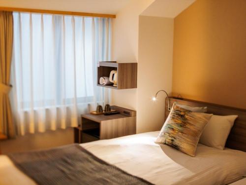a bedroom with a bed with a pillow and a window at Giappo Franca Kyoto in Kyoto