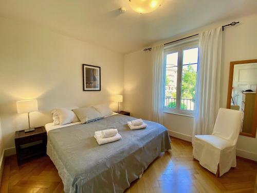 a bedroom with a bed and a chair and a window at Very nice apartment close to the lake in Lausanne