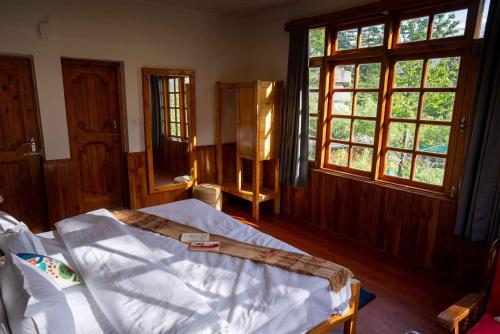 a bedroom with a bed in a room with windows at Zen Manali by Keekoo Stays in Manāli