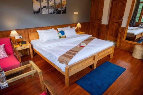 a bedroom with a large bed and a red couch at Zen Manali by Keekoo Stays in Manāli