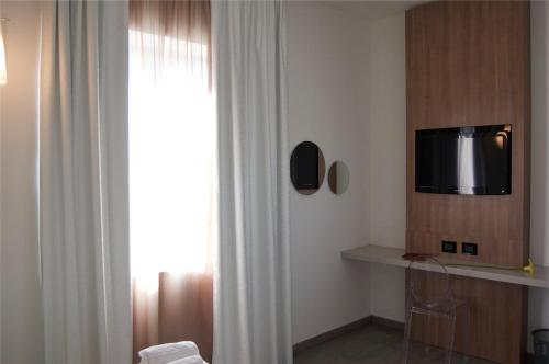um quarto com uma televisão numa parede ao lado de uma janela em Motel S.16 em Muro Leccese