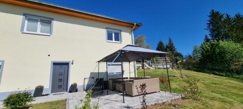 a white house with an umbrella in the yard at Ferienwohnung Bergidyll in Schwarzenberg (Erzgebirge)