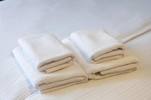 una pila de toallas sentadas encima de una cama en Hit Hotel en Varsovia