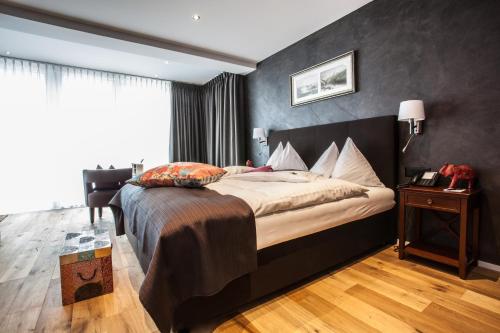 a bedroom with a large bed with a black wall at Hotel Riviera Loft in Weggis