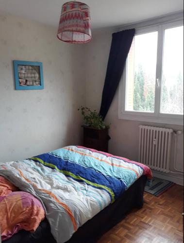 - une chambre avec un lit et une couverture colorée dans l'établissement appartement Velotte, à Besançon