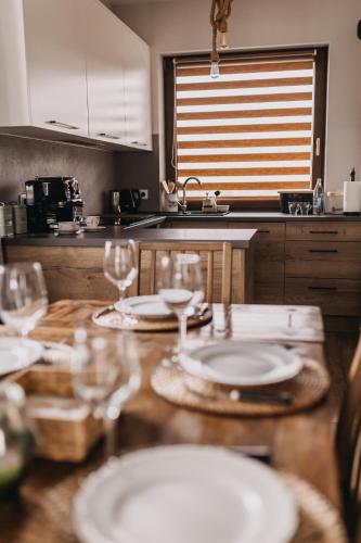 a kitchen with a wooden table with plates and glasses at Dzikowiejsko in Bardo