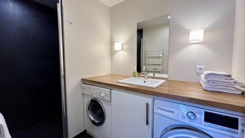 une salle de bain avec une machine à laver et un lavabo dans l'établissement L'ECHAPPEE BAIE, au Crotoy