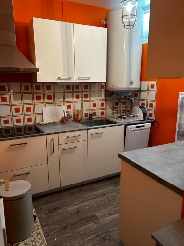 - une cuisine avec des placards blancs et un mur orange dans l'établissement Appartement La Maison d Ulysse, à Saint-Hilaire-de-Riez