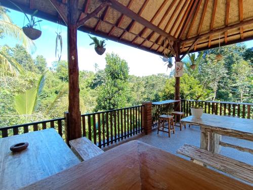 a patio with a table and benches on a deck at Artomoro Bali in Munduk