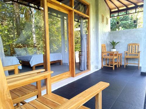 eine Veranda mit einem Bett, einem Tisch und Stühlen in der Unterkunft Artomoro Bali in Munduk