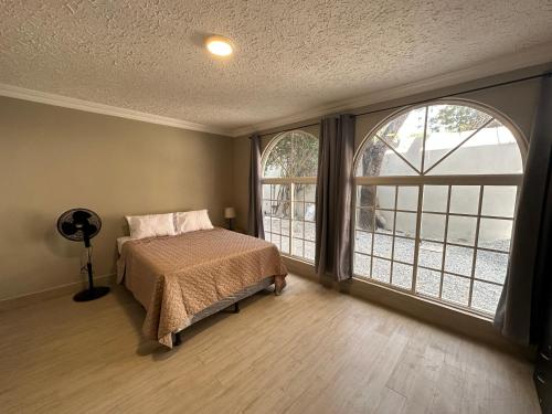um quarto com uma cama e 2 janelas grandes em Villa Sicilia em Guatemala